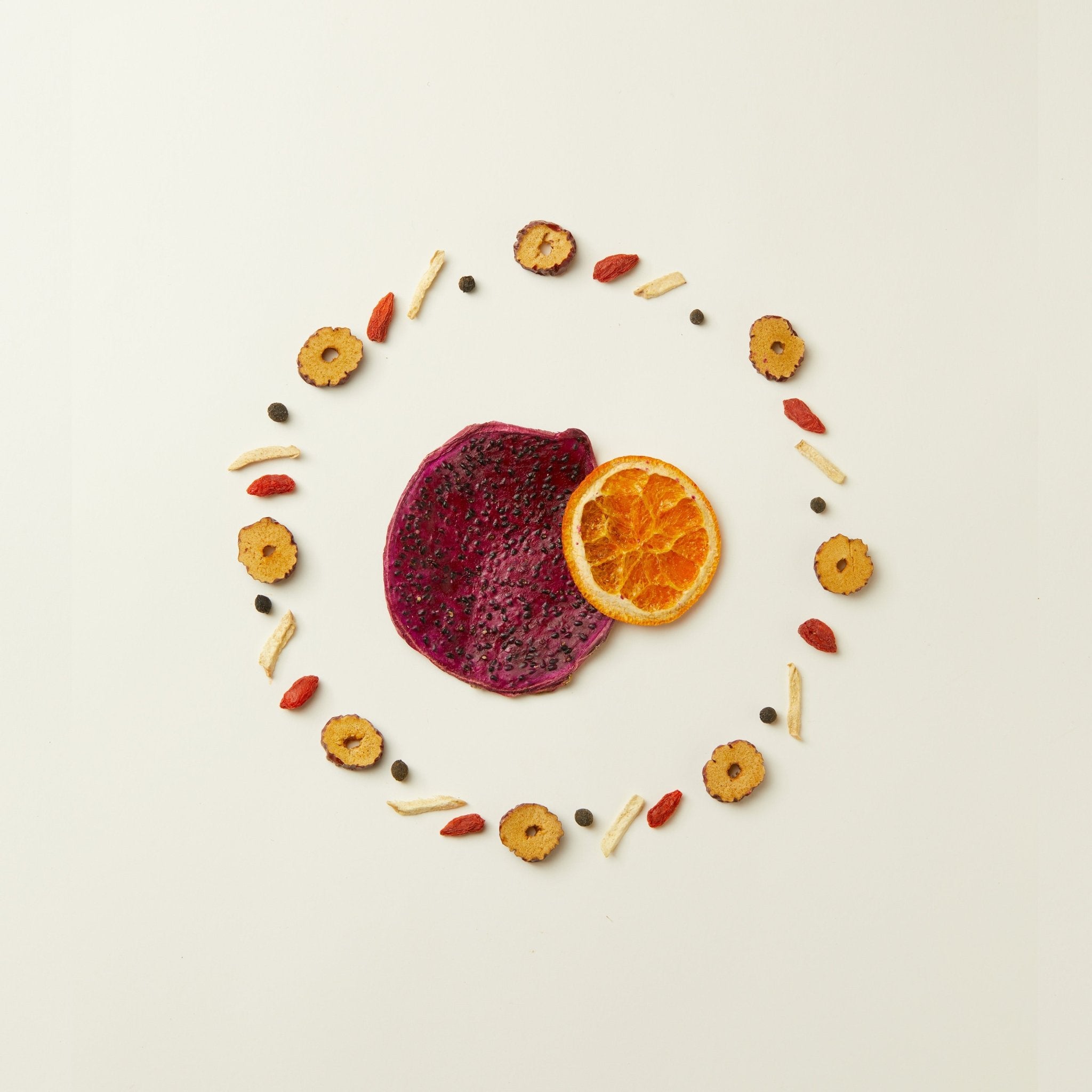 Enjoy Chafolio Dragonfruit Ginger Tea alongside a vibrant circular display of dried fruits and seeds, centered with dragon fruit and orange slices—a perfect pairing for digestive support.