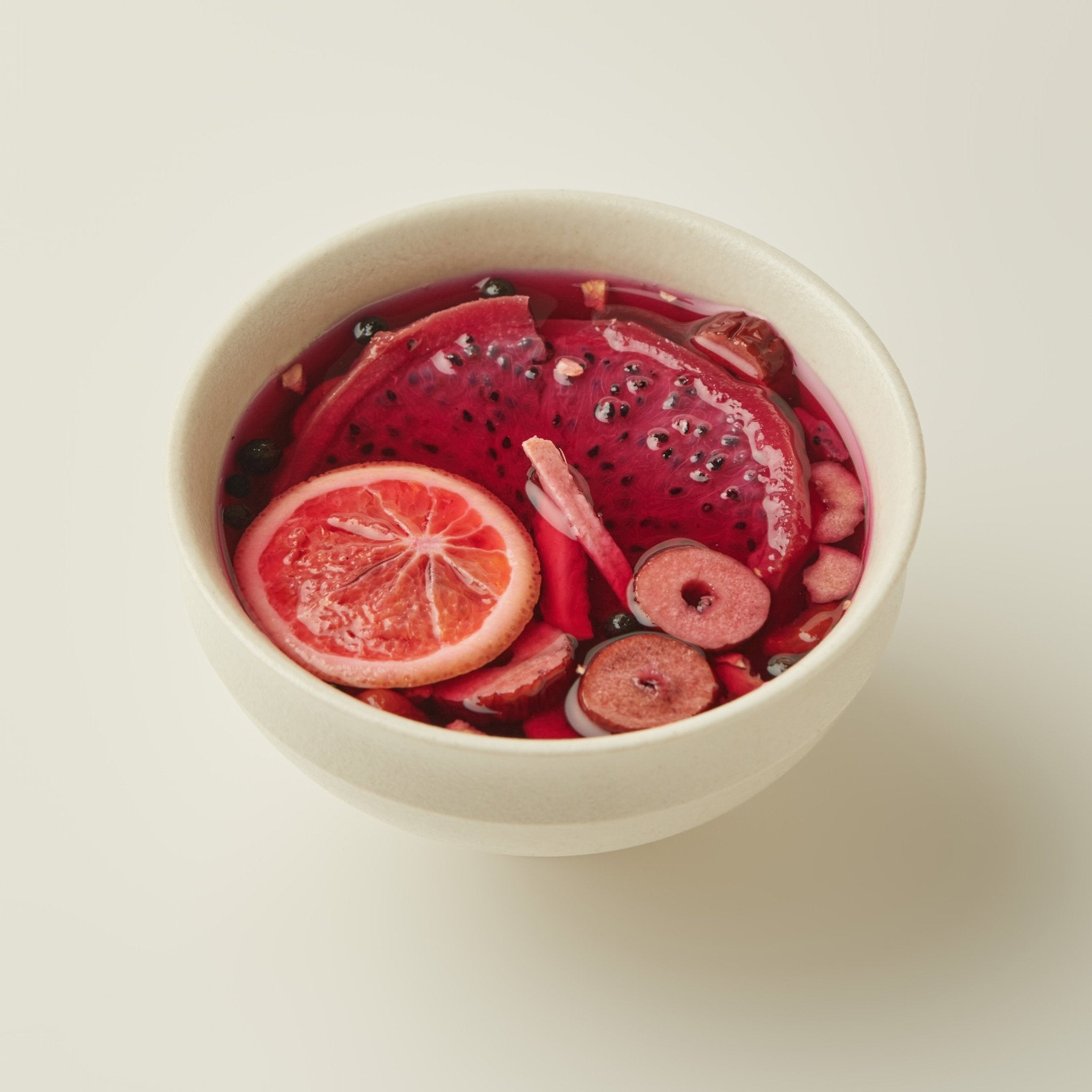 Chafolio's Dragonfruit Ginger Tea comes in a beige bowl, brimming with citrus slices and dried fruits for a vibrant, refreshing brew—ideal for gentle digestive support.