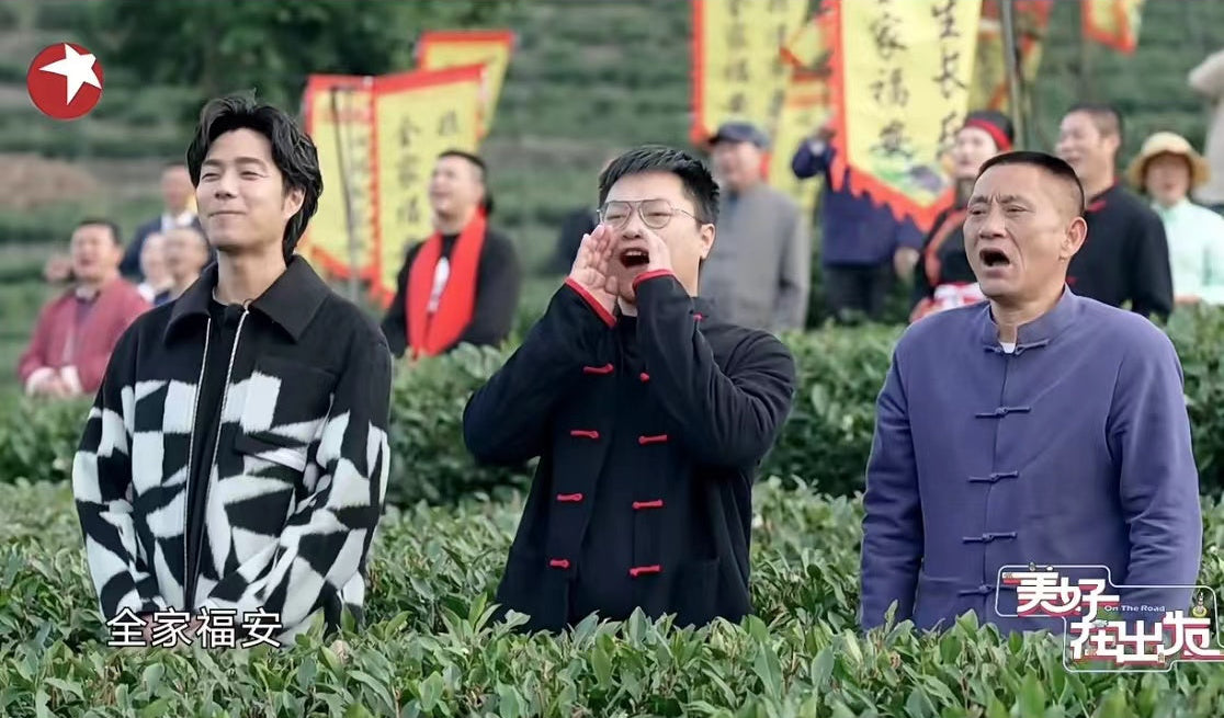 Three men stand together in a tea field, with one shouting. People holding colorful banners are visible in the background. Chinese text appears on the image.