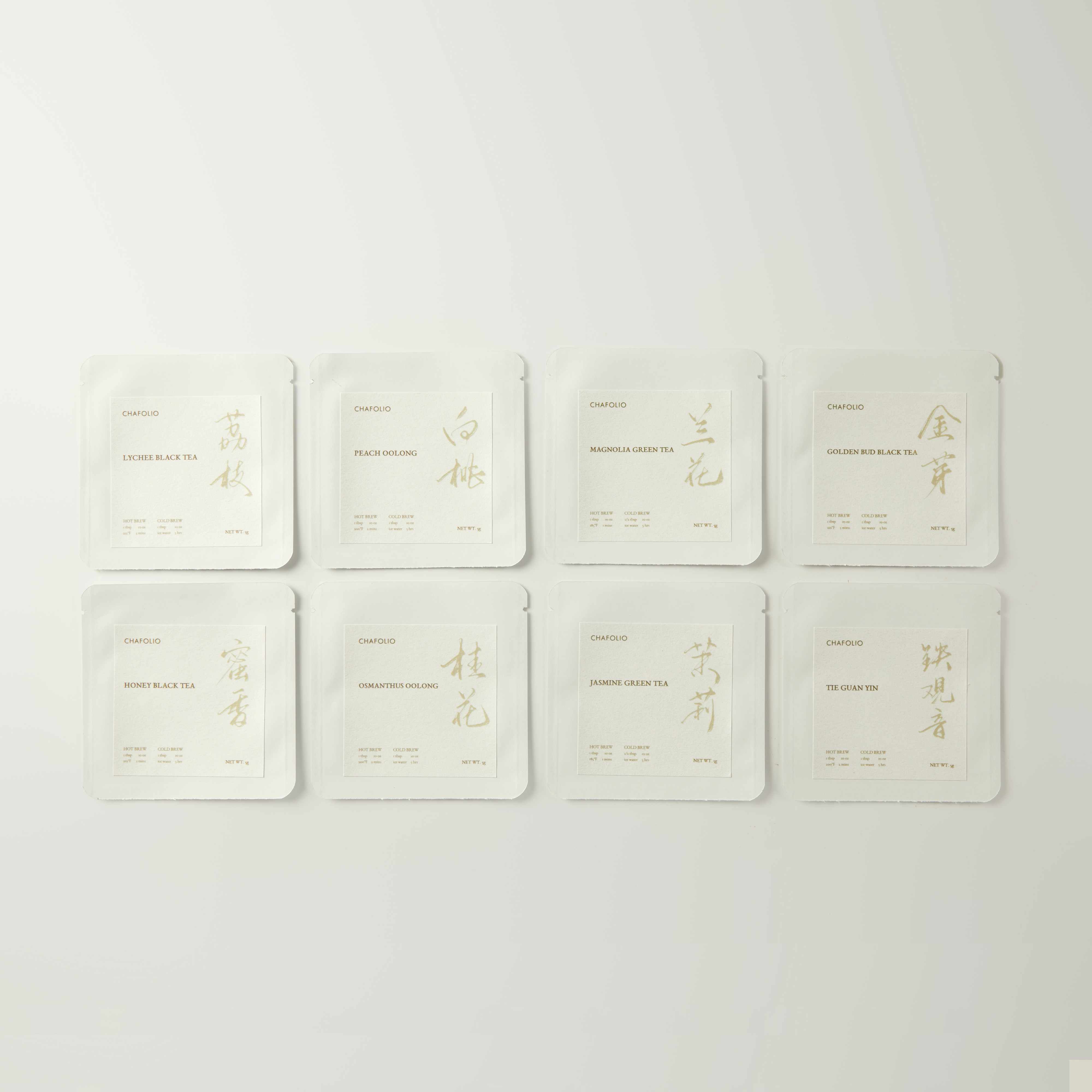 Eight white packets from Chafolio's Discovery Set | Curated Tea Selection, featuring Oolong Tea and Jasmine Green Tea in gold and silver text, are arranged in two rows on a light background.