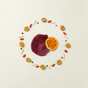 A slice of dragon fruit and dried orange among assorted fruits and seeds forms a colorful scene—perfect inspiration for the Chafolio Mother’s Day Herbal Tea Set, a naturally caffeine-free herbal tea bundle.