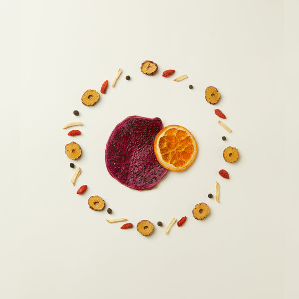 A slice of dragon fruit and dried orange among assorted fruits and seeds forms a colorful scene—perfect inspiration for the Chafolio Mother’s Day Herbal Tea Set, a naturally caffeine-free herbal tea bundle.