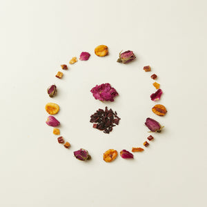 A loose oval of dried rosebuds, hibiscus petals, and assorted dried fruit from the caffeine-free Chafolio Mother’s Day Herbal Tea Set is displayed on a plain white background.