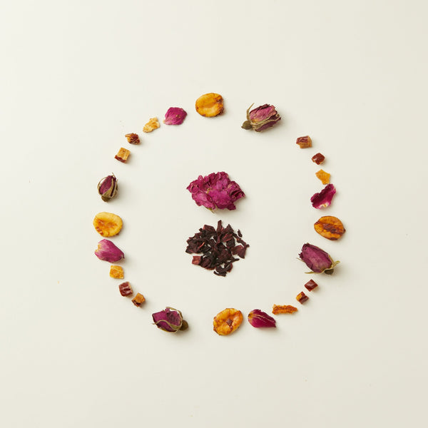A loose oval of dried rosebuds, hibiscus petals, and assorted dried fruit from the caffeine-free Chafolio Mother’s Day Herbal Tea Set is displayed on a plain white background.
